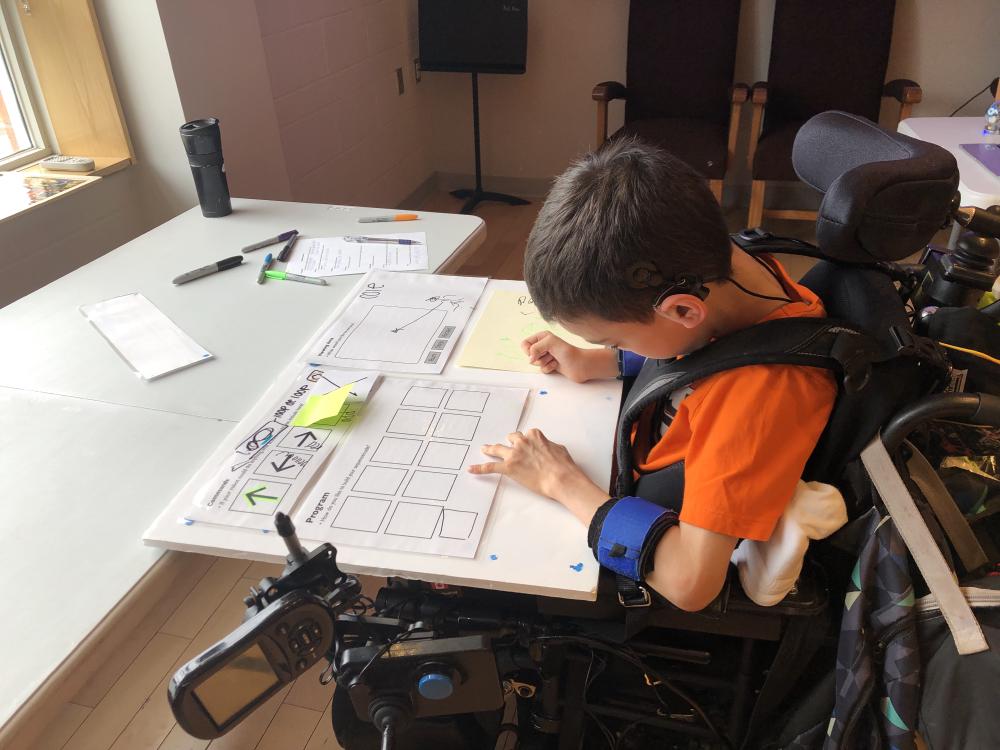 child in a mobility device with a foam board and sticky notes