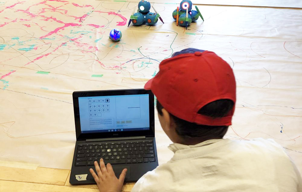 Student using Weavly simple prototype to build a program to direct robots on the floor.