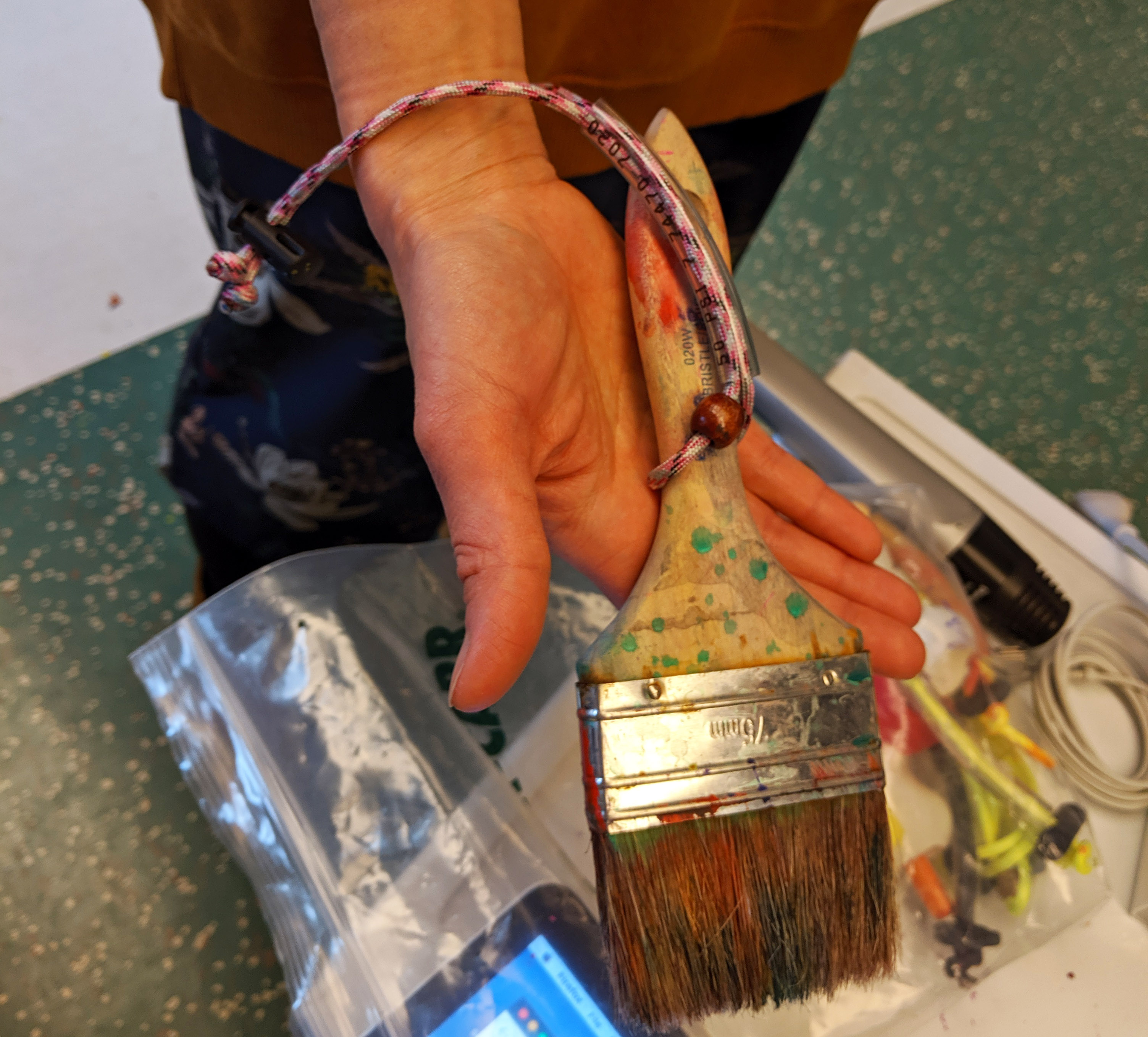 Using a tie to wrap a brush around the student's wrist for further support