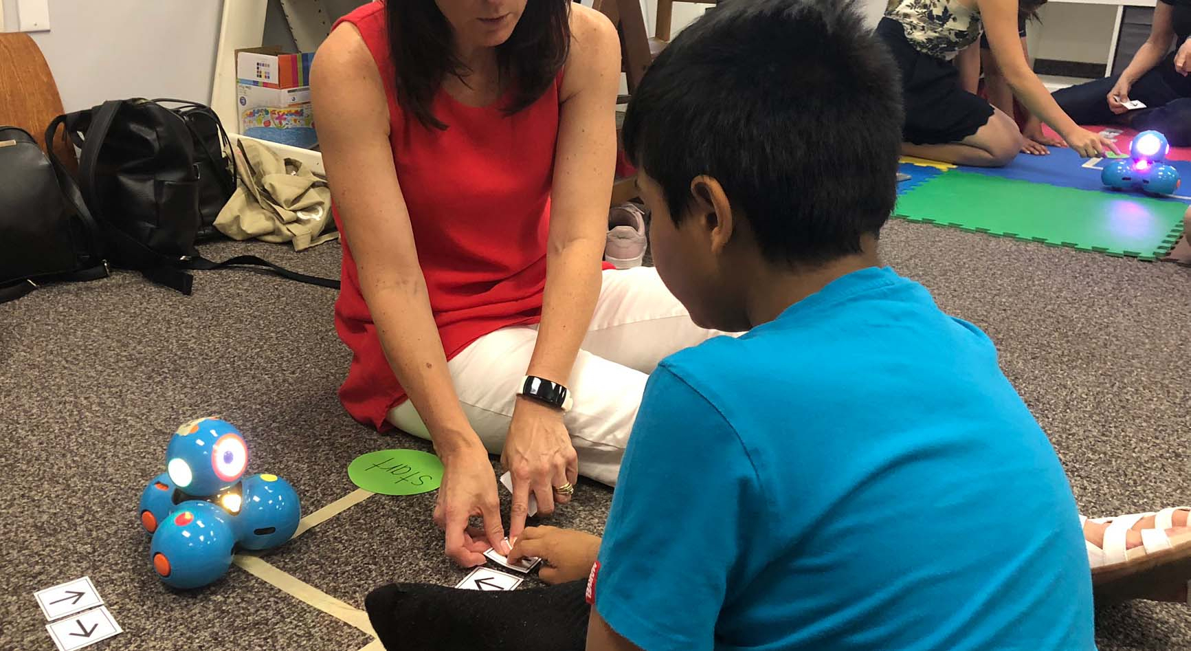 Facilitators are working with students in separate stations to work with robots