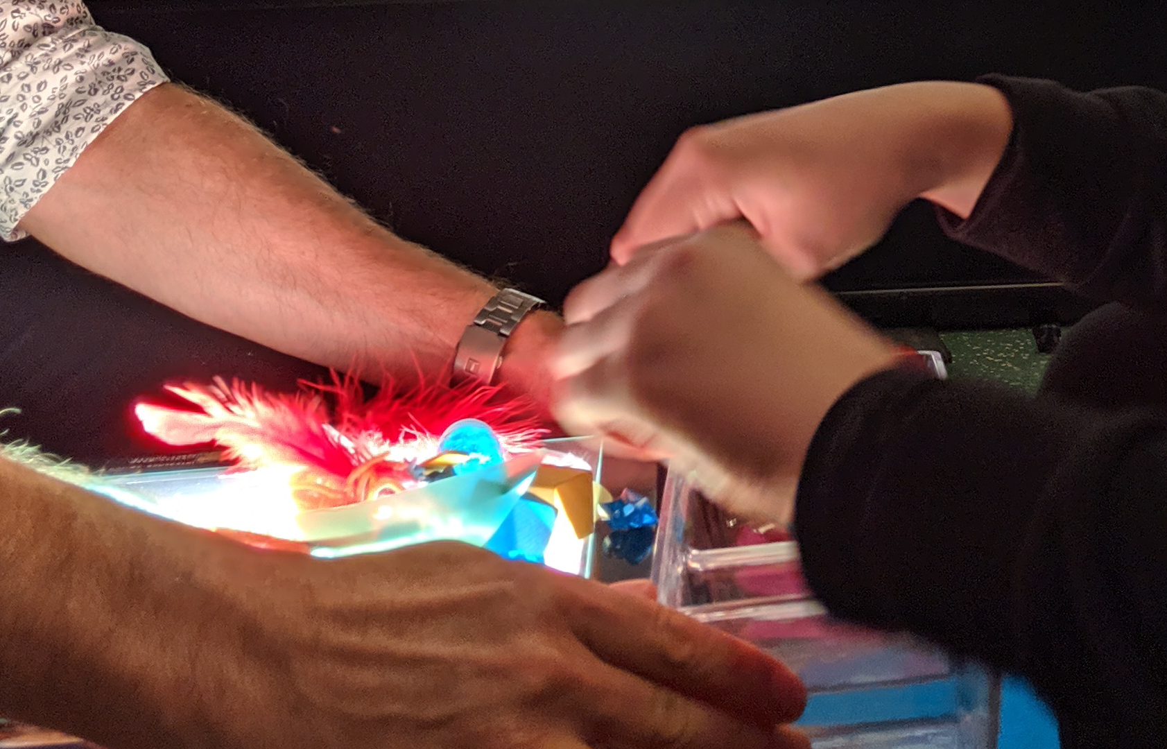 Hands of an adult and a child working through different items in a sensory bin